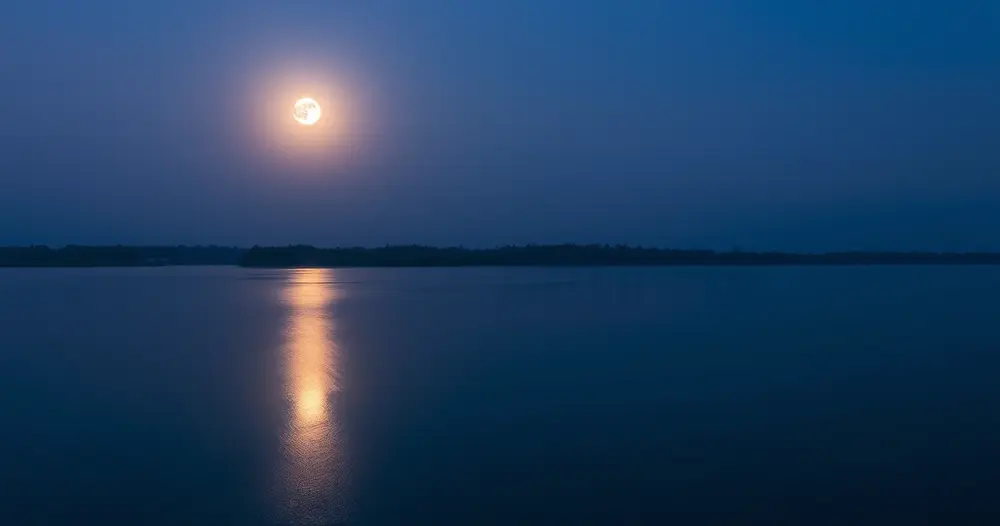 Lua cheia refletida em um rio calmo ao anoitecer com linha de árvores ao fundo